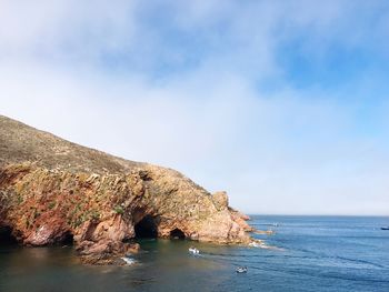 Rock formation by sea against sky