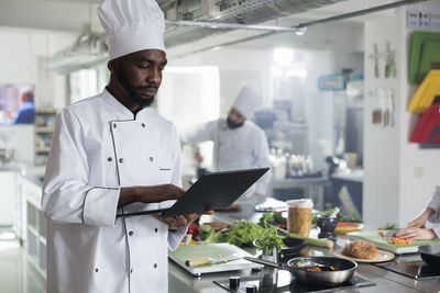 Chef using laptop while standing in commercial kitchen