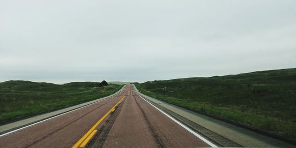 Road amidst field against sky