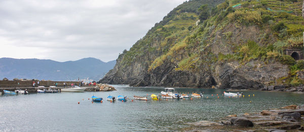 People on boats in sea against mountains