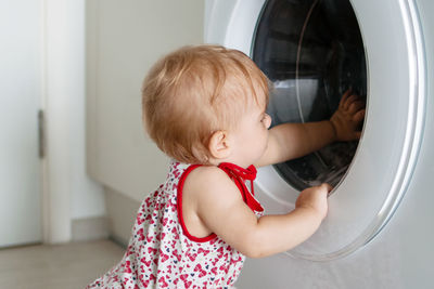 Side view of cute girl by washing machine
