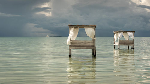 Wooden posts in sea against sky