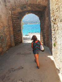 Woman walking under arch discovering fortress spinalonga, greece.