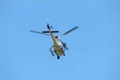 Low angle view of helicopter flying against clear blue sky