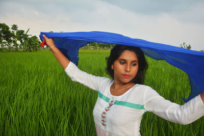 Portrait of woman standing on field against sky