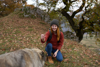 Full length of a smiling young woman sitting on plants