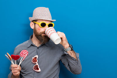 Low angle view of man wearing sunglasses against blue background