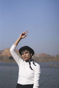 Young woman sanding by lake against sky