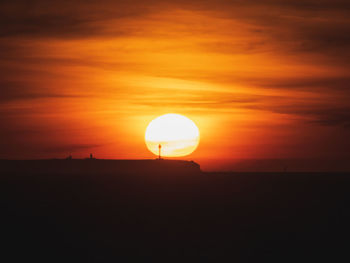 Silhouette landscape against orange sky