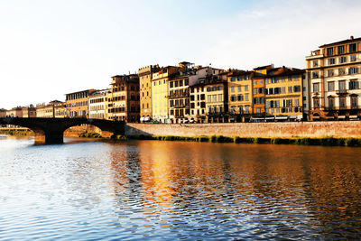 Ponte santa trinita over arno river by buildings at tuscany against clear sky