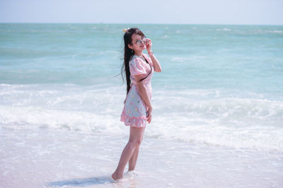 Young woman in sunglasses standing in sea