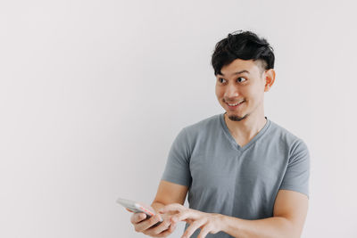 Portrait of young man using smart phone against white background