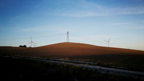 Electricity pylons on landscape against sky