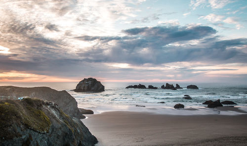 Rocks on beach against sky during sunset