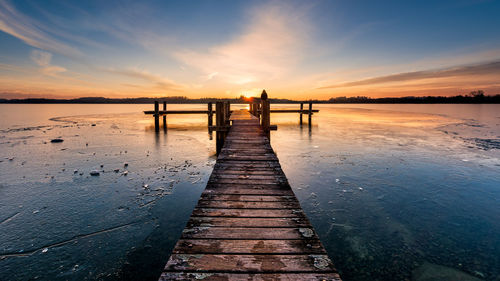 Pier over sea against sky during sunset