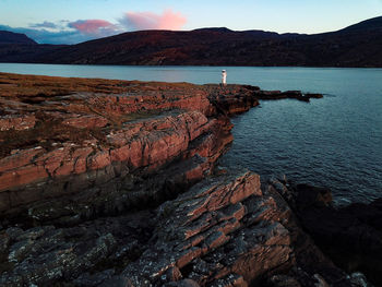 Rocks on shore by sea against sky