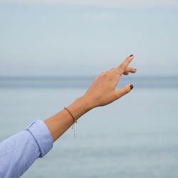Cropped hand of woman against sea