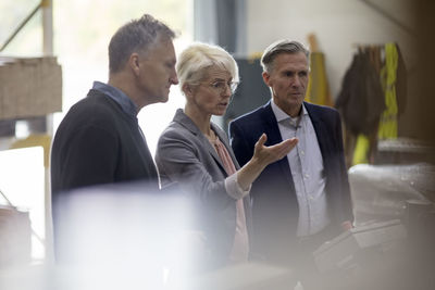 Businesswoman gesturing while discussing with colleagues at industry