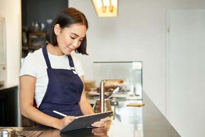 Side view of young woman using digital tablet at home