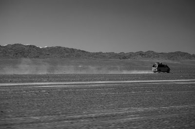 Scenic view of desert by road against clear sky