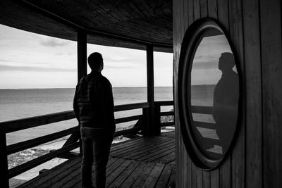 Rear view of man looking at sea against sky