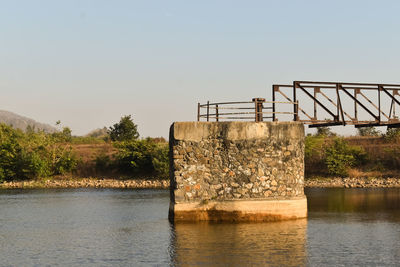 Old bridge over river against clear sky