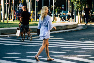 Rear view of people walking on road in city