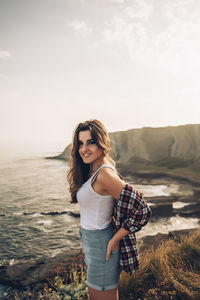 Beautiful young woman standing on land against sky