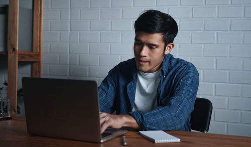 Young man using mobile phone while sitting on table