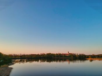 Scenic view of lake against clear blue sky during sunset