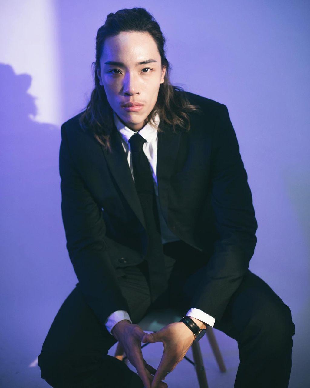 YOUNG MAN STANDING AGAINST BLUE WALL