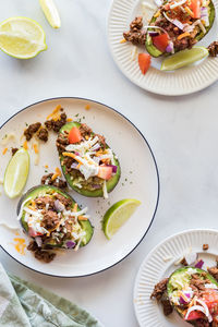 Avocado boats topped with taco fixings, ready for eating.