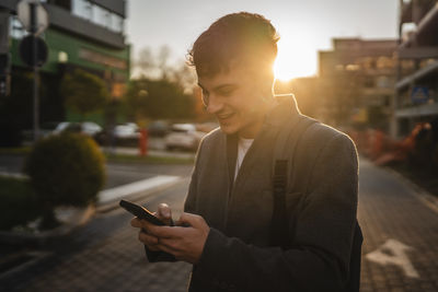 Young man using mobile phone in city