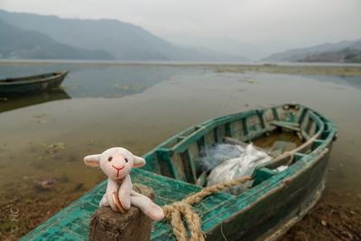 Abandoned toy boat on land against sky