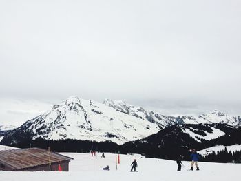 People on snow covered landscape against sky