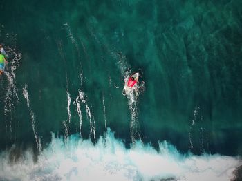 Blurred motion of man with surfboard in sea