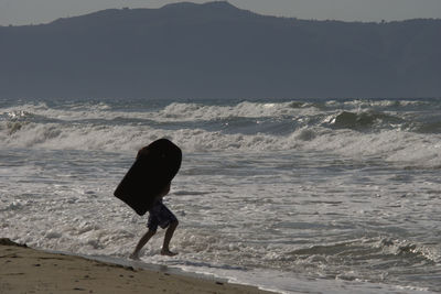 Full length of silhouette person on beach against sky