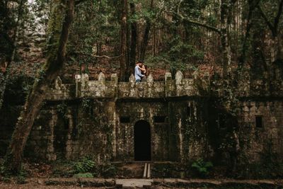 Man standing by stone wall in forest