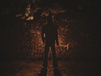 Full length of man standing with axe on field at night