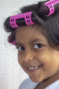 Portrait of girl with hair curlers against wall at home