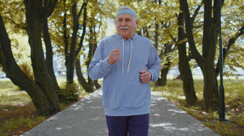 Senior man listening music while jogging in park