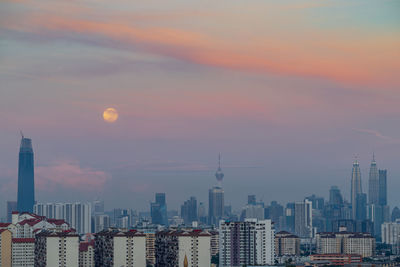 Buildings in city against sky during sunset