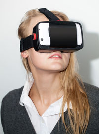 Young woman wearing virtual reality simulator against white background