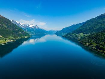 Scenic view of lake and mountains against blue sky