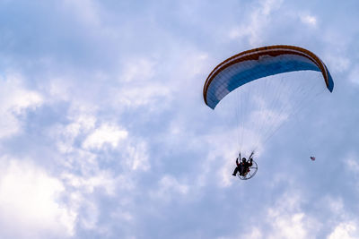 Low angle view of person paragliding against sky