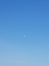 Low angle view of moon against clear blue sky