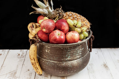 Close-up of fruits in container on table against black background