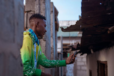 Portrait of young man looking using a mobile phone in the slums