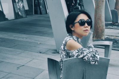 Side view of young woman wearing sunglasses in city