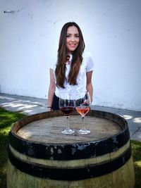 Portrait of smiling young woman standing by wine cask